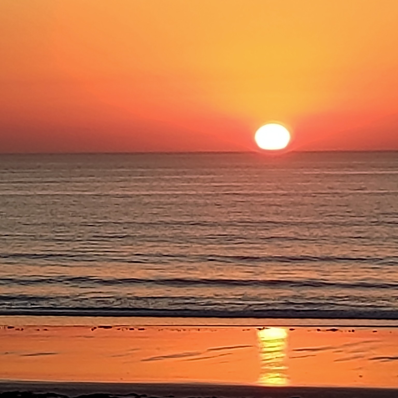 Sun reflected in waves and wet sand